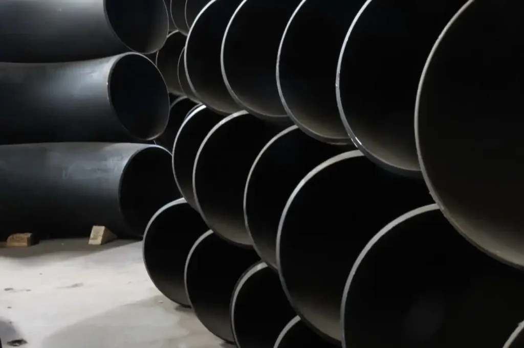Fittings Pipechem warehouse stack of large-diameter carbon steel pipe elbows and 90-degree bends